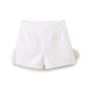 Close-up of white high-waisted shorts with hollow eyelet embroidery and side tie bows