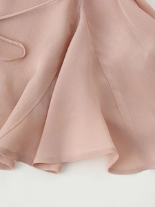 Detailed macro view of the ruffled hemline and drawstring on the light pink v-neck shirt
