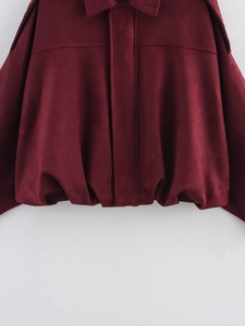 Detail of dark red bomber jacket showing suede texture and pleated elastic hemline