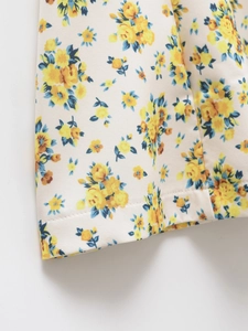 Close-up of yellow floral print fabric showing high-quality hemmed edges and stitching