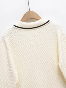 Detailed view of cable-knit texture and contrasting collar stripes on cream sweater