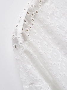 Détail d'une robe blanche en broderie anglaise avec des motifs de marguerites délicats