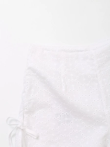 Detailed close-up of white hollow embroidery fabric and side drawstring on high waist shorts