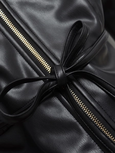 Detail of black leather jacket featuring a tie-knot bow and premium gold metal zipper