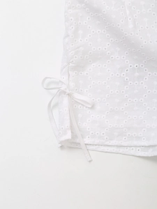 Detailed macro view of white hollow embroidery fabric with delicate lace bow ties