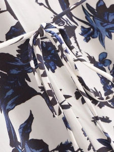 Détail de la ceinture à nœud sur robe d'été à col en V avec imprimé floral bleu élégant