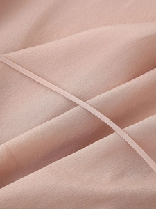 Macro shot of soft pink chiffon fabric texture with delicate stitching details for women's blouse