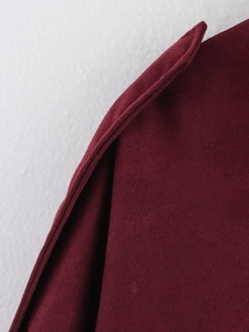 Macro shot of burgundy faux suede fabric texture and stitching details on the bomber jacket