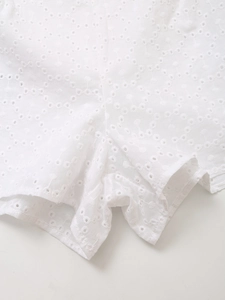Detailed view of white eyelet embroidery fabric with geometric floral patterns