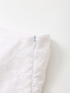 Detail of white hollow embroidery fabric with a concealed water-drop zipper