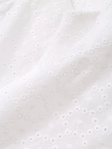 Close-up of white summer outfit showing intricate eyelet embroidery and hollowed-out fabric