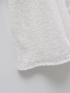 Gros plan détaillé sur la délicate broderie anglaise florale d'une robe blanche à col en V