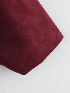 Detailed close-up of dark red faux suede fabric texture for luxury bomber jacket