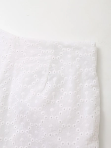 Close-up of white broderie anglaise embroidery on high waist shorts and lace-up top set
