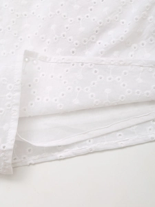 Detailed macro view of white Broderie Anglaise hollow embroidery fabric with clean hem
