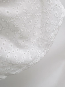 Gros plan détaillé sur la broderie florale de marguerite blanche sur un tissu en coton doux