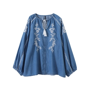 Detailed embroidery on a dark blue denim shirt with white floral patterns and tassels