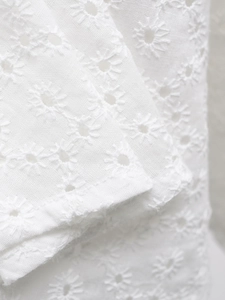 Détail d'une robe en coton blanc avec broderie anglaise marguerite et texture florale