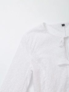 Detailed view of white eyelet embroidery blouse with lace-up neck and XS size tag