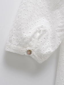 Vue macro de broderie anglaise avec un bouton scintillant sur le détail du poignet
