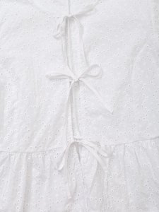 Detail of white eyelet lace embroidery with elegant front tie-bow closures and texture