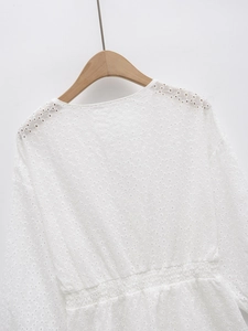 Détails de la blouse blanche en coton avec broderie anglaise marguerite et dos smocké