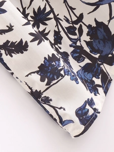 Détail du tissu à fleurs montrant des coutures de qualité et un motif de feuilles bleues