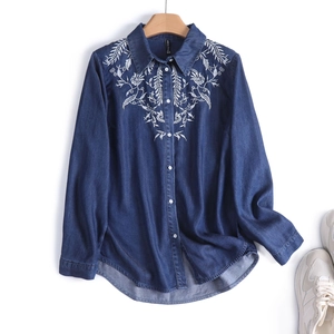 Detailed white floral embroidery on the collar of a dark blue denim long-sleeved shirt