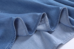 Close-up detail of vintage denim shirt hem featuring double-row stitching on blue fabric