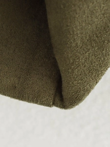 Close-up of olive green suede jacket material showing soft matte texture and fine stitching