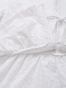 Detail of white cotton eyelet embroidery blouse with lace-up front and ruffled edges