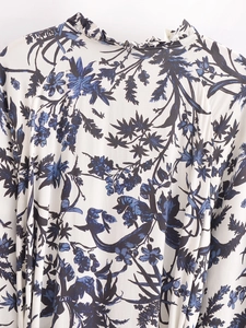 Détail du col à volants et de l'imprimé floral bleu sur robe en coton blanc