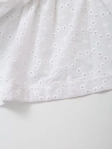 Close-up of white broderie anglaise fabric with intricate hollow embroidery and rolled hem