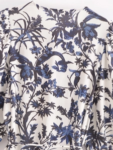 Dettaglio dell'abito bianco con stampa floreale blu, scollo rotondo e cintura in tessuto