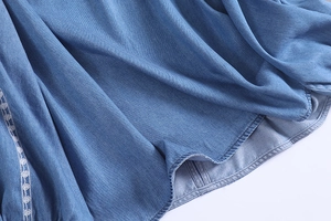 Detail of blue denim fabric with delicate white embroidery and washed texture