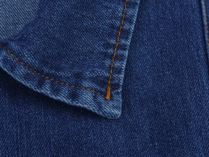 Close-up of navy denim fabric with orange double stitching and twill texture detail