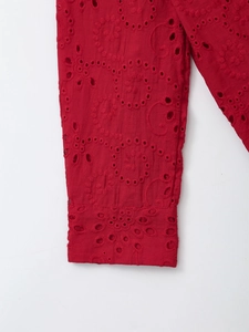 Close-up of red cotton shirt featuring intricate floral eyelet embroidery and hollowed details