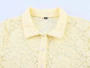 Détail du col d'une chemise en dentelle jaune clair avec boutons et motifs floraux