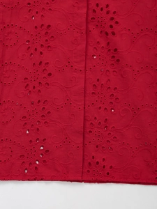 Close-up of red floral eyelet embroidery and intricate broderie anglaise fabric detail