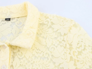 Vue macro détaillée du col en dentelle au crochet jaune pâle avec boutons blancs et étiquette
