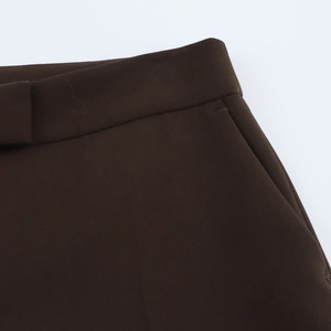 Détails de la taille d'un pantalon marron foncé montrant la poche latérale et le tissu