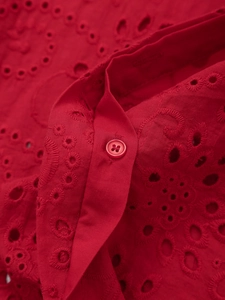 Macro view of red cotton shirt with hollow eyelet embroidery and matching four-hole button