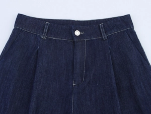 Gros plan détaillé d'un pantalon en jean bleu foncé à taille haute avec bouton en métal