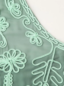 Dettaglio dei raffinati ricami soutache su tessuto a trama verde menta di classe