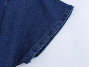 Detailed close-up of navy blue denim fabric with contrast yellow double-stitch seams