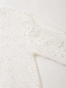 Detailed close-up of white hollow embroidery pattern on a long sleeve shirt