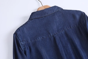Detail of indigo denim shirt stitching and collar construction on a wooden hanger