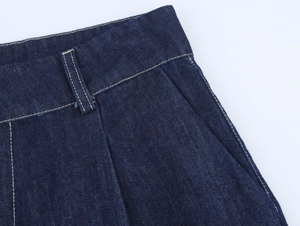 Détail de la taille en denim bleu foncé avec coutures contrastées et poche inclinée