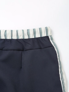 Detail of elastic waistband and side stripes on dark blue casual women's trousers