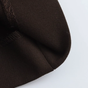 Gros plan détaillé du tissu en maille marron foncé montrant les coutures raffinées